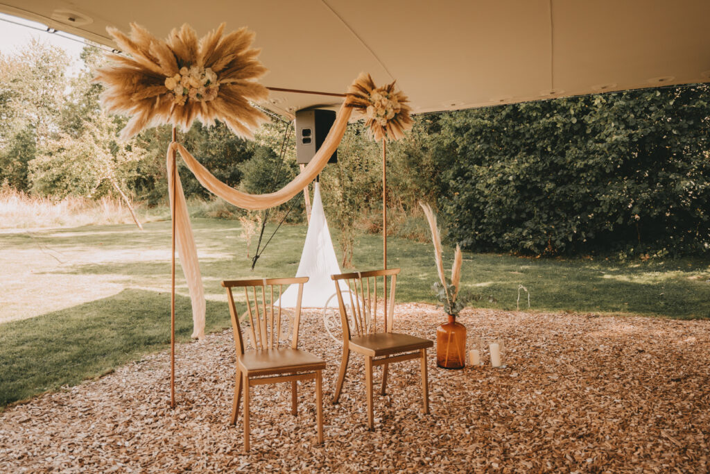 Man sieht einen wunderschönen Boho Traubogen mit Stühlen davor Vanessa Grasser Worte mit Herz freie Reden