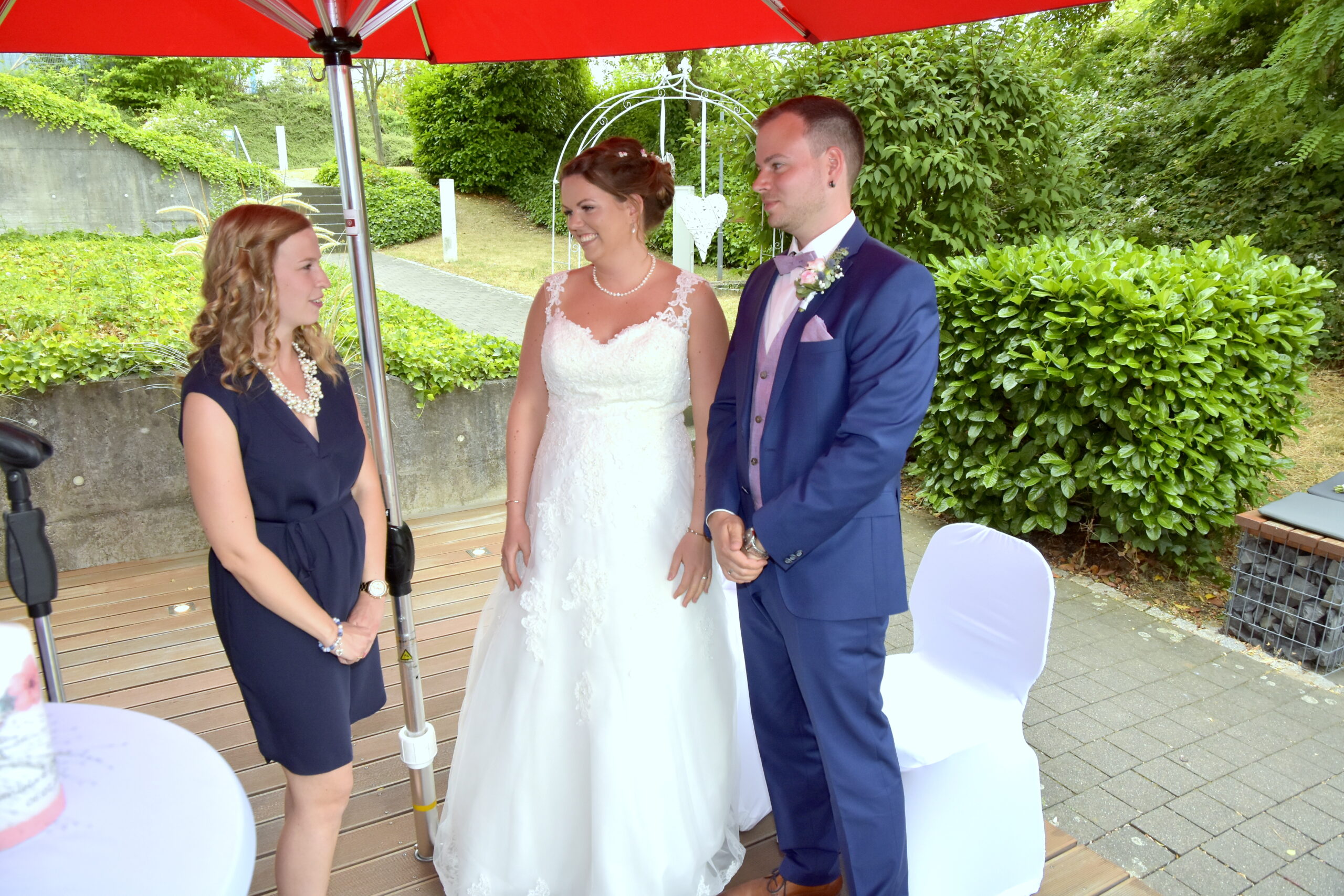 Brautpaar spricht mit freier Rednerin Vanessa Grasser auf ihrer freien Trauung im Grünen